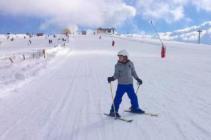 Person skiing on Serra da Estrela's snowy slopes under a clear blue sky, perfect for a Lisbon private tour adventure.