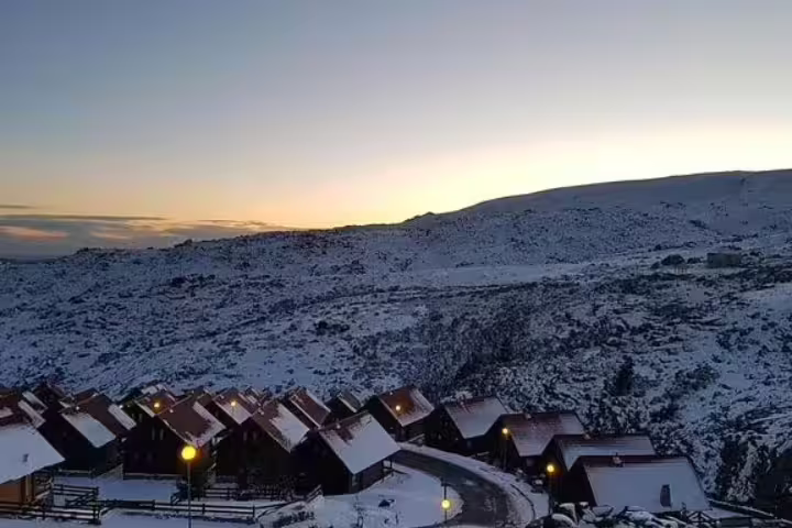 Snow-covered chalets at sunset in Serra da Estrela, highlighting the serene beauty of Portugal's highest mountain range on a private tour.