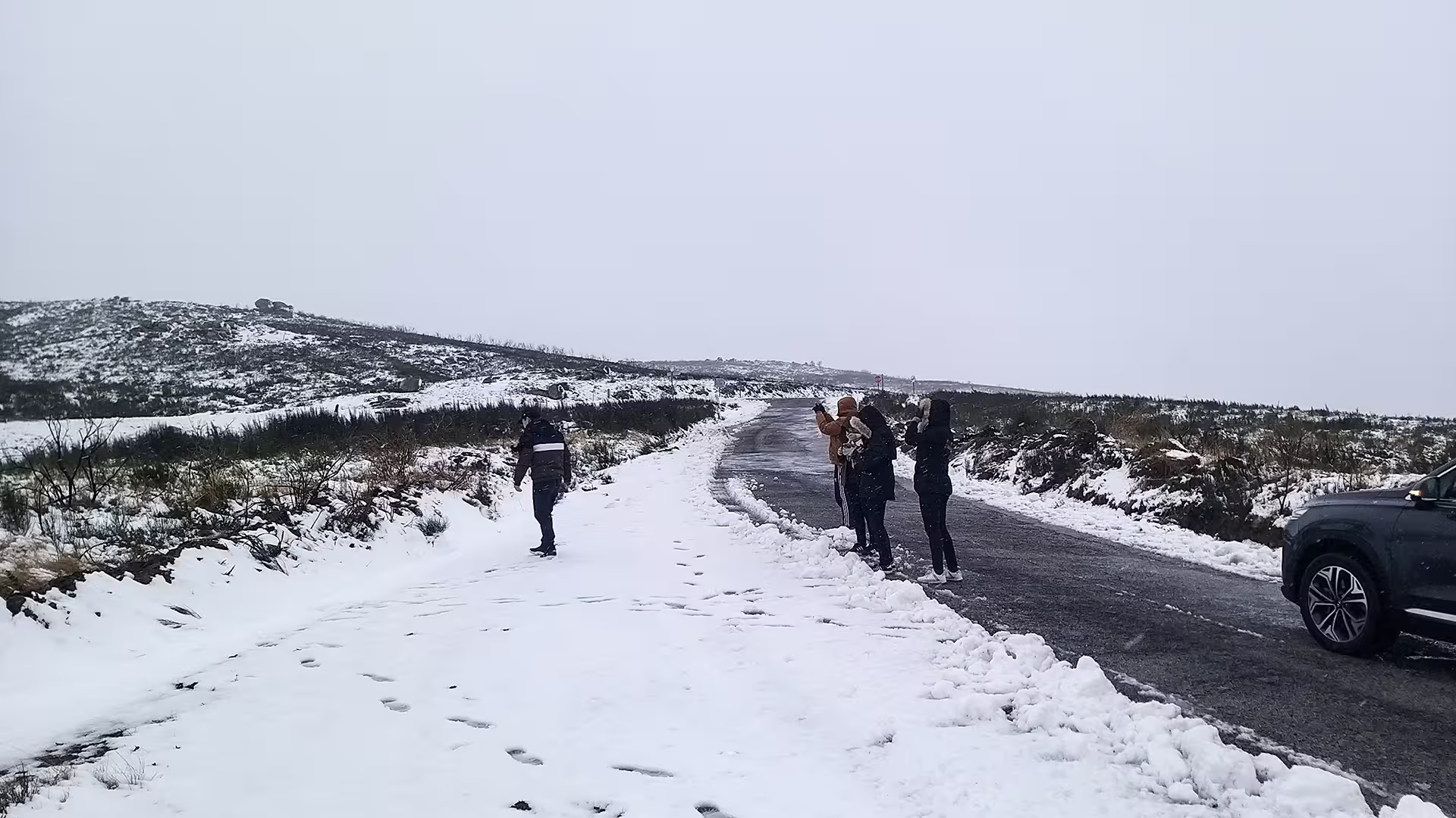 Visitors enjoy a snowy landscape in Serra da Estrela Park, capturing moments on a private tour known for its famous cheese.
