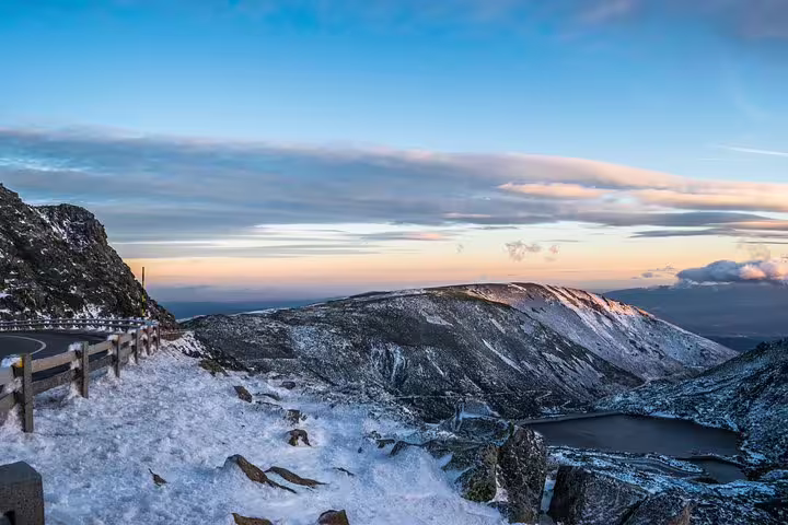 Breathtaking snowy mountain view of Serra da Estrela at sunrise, showcasing a vast landscape and tranquil lake.