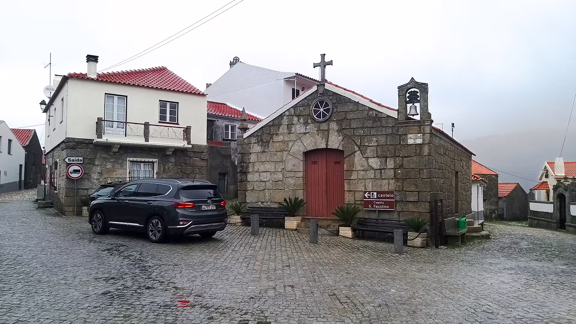 Charming village scene in Serra da Estrela Park, featuring stone chapel and cobblestone street, perfect for a private tour experience.