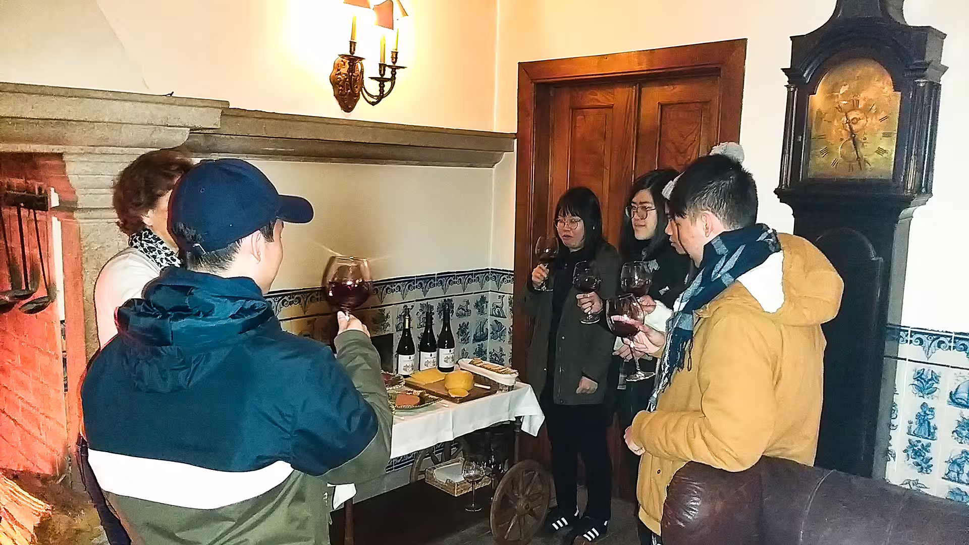 Group enjoying wine and cheese tasting by a cozy fireplace during a private tour of Serra da Estrela Park, Portugal.