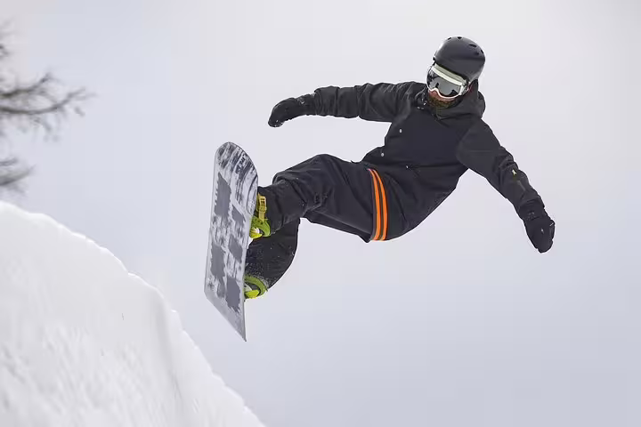 Snowboarder catching air on a snowy slope in Serra da Estrela, perfect for adventure on a private tour from Lisbon.