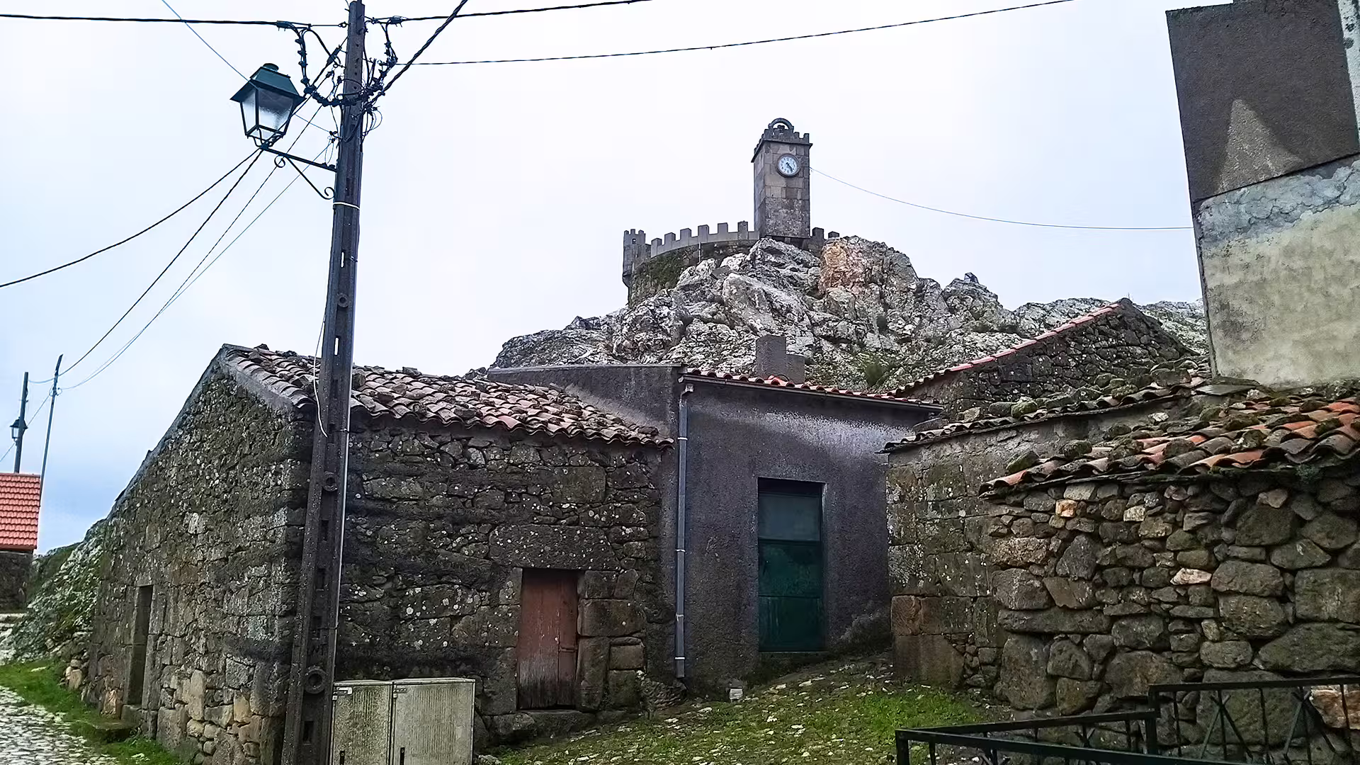 Rustic stone houses with a historic clock tower in Serra da Estrela Park, perfect for a private tour and cheese tasting experience.