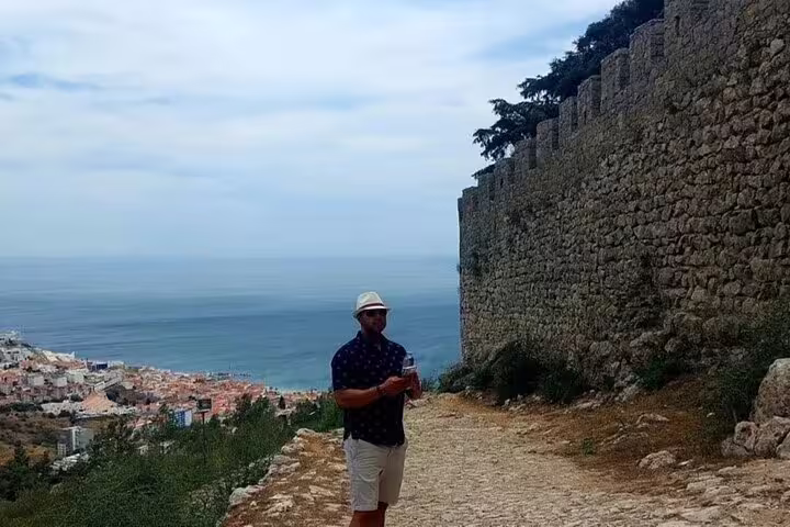 Man explores scenic coastal view at Sesimbra Castle during Private Azeitão Cheese Workshop and Wine Tasting Tour.