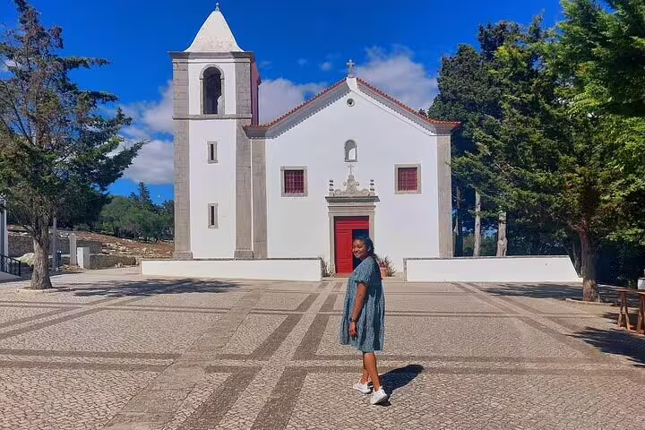 Visitor exploring historic church architecture in picturesque Sesimbra during a Private Azeitão Cheese and Wine Tasting Tour.