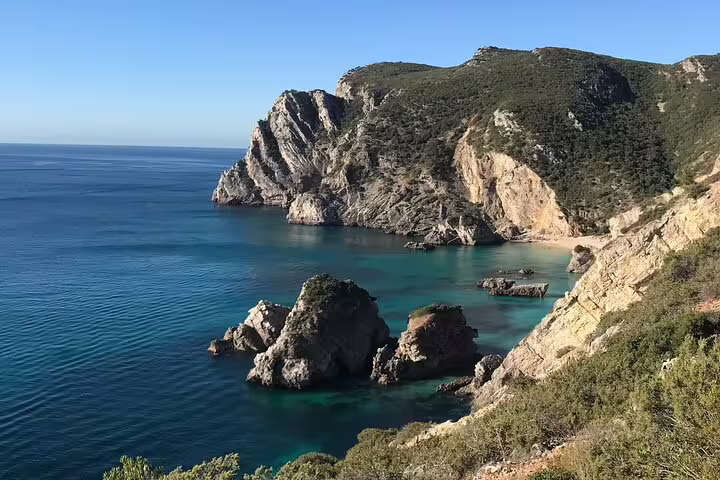 Scenic view of Sesimbra's rugged coastline and turquoise waters in Arrábida Natural Park, perfect for a kayaking adventure.