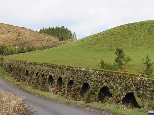 Historic moss-covered aqueduct and rolling green hills seen on the Sete Cidades Jeep Tour in São Miguel, Azores