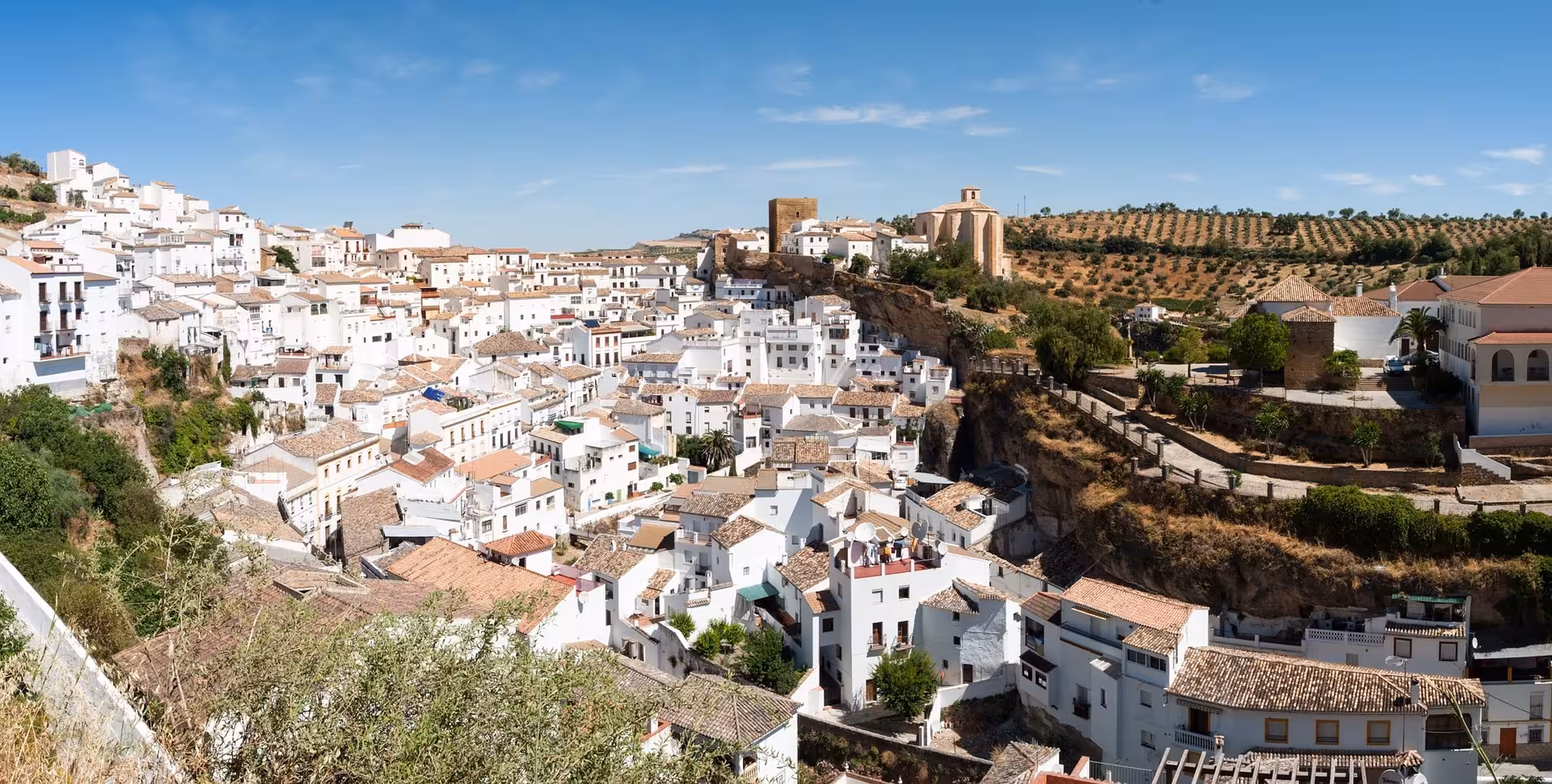 Panoramic view of Setenil de las Bodegas with traditional Andalusian architecture and rocky landscape under a sunny sky.