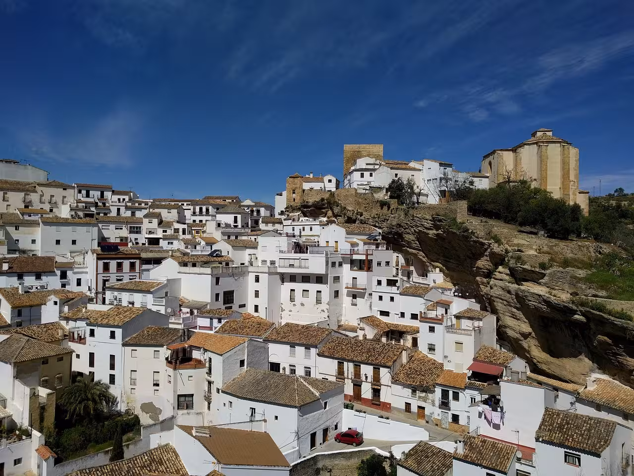 Whitewashed houses of Setenil de las Bodegas nestled into rock formations under a clear blue sky.