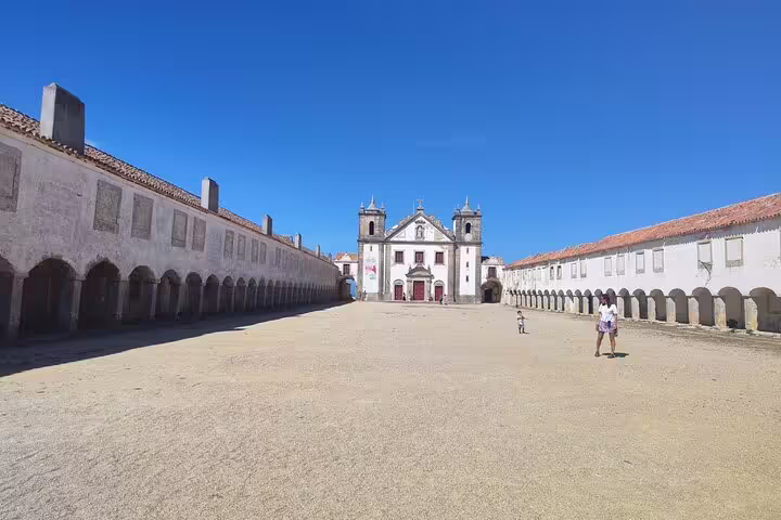 Historical courtyard leading to a grand church facade under a clear blue sky in Setúbal, Portugal.