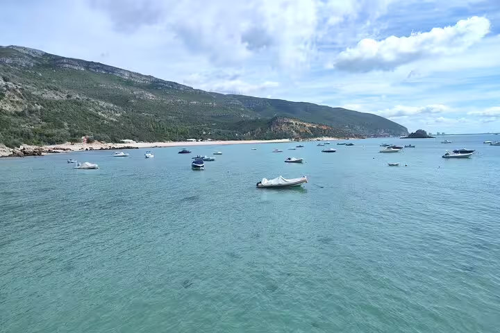 Scenic view of boats floating on turquoise waters with lush hills in Setúbal, ideal for nature and culture tours.