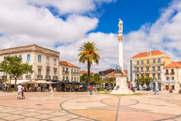 Sunny town square in Setúbal with a statue and palm tree, a highlight of the Arrábida tour from Lisbon.