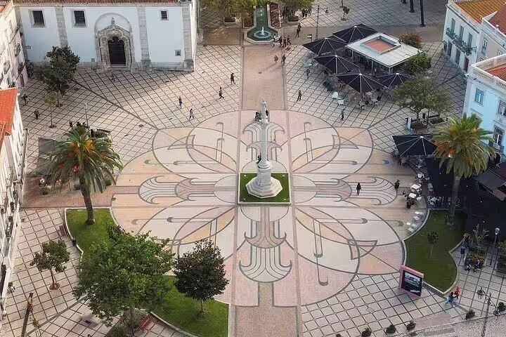 Explore Setúbal's intricate town square with a striking geometric pattern and a central statue, inviting cultural exploration.