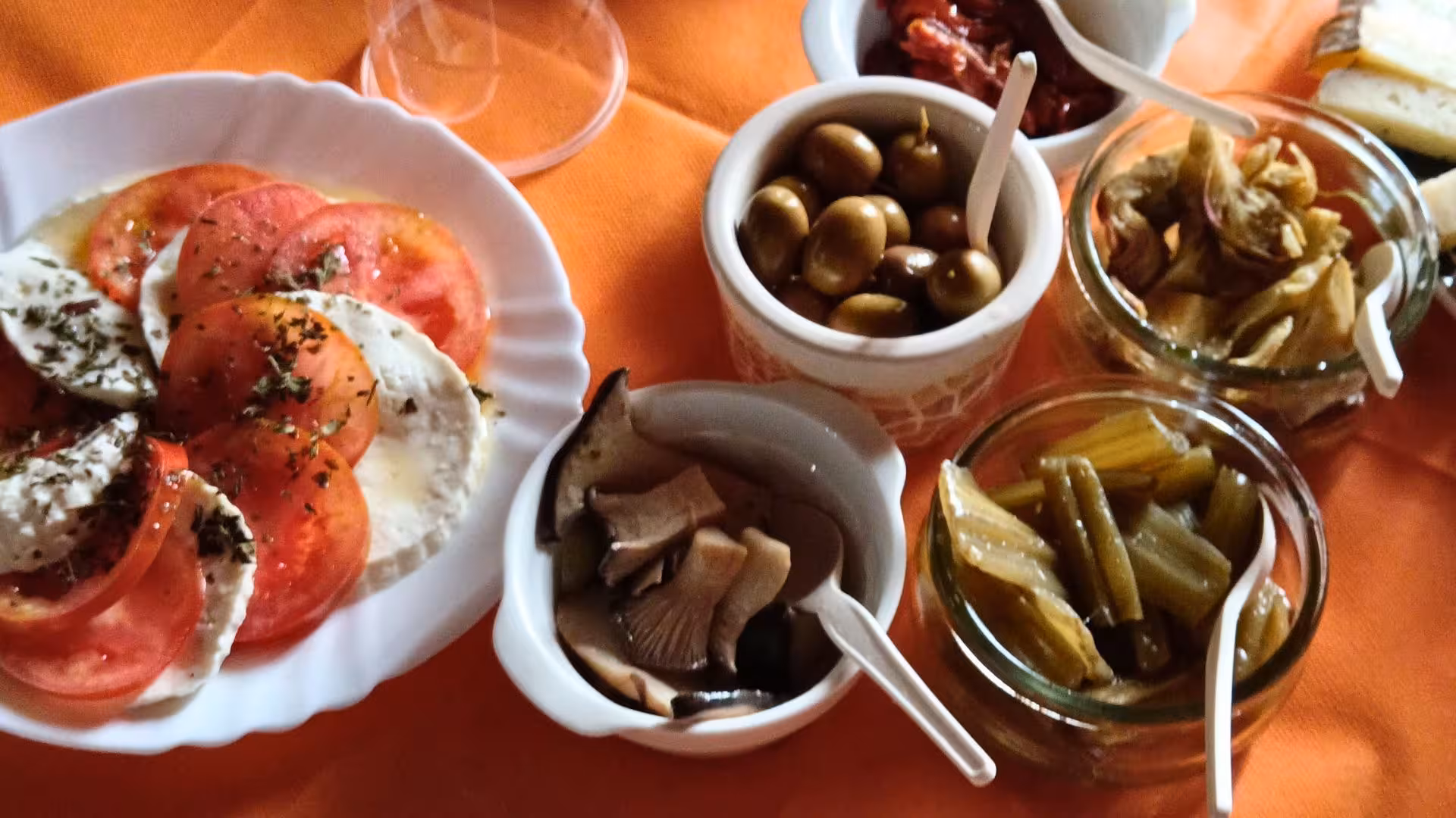 Assortment of local Sardinian delicacies with olives, mushrooms, and tomatoes for Seulo farm tour tasting experience.