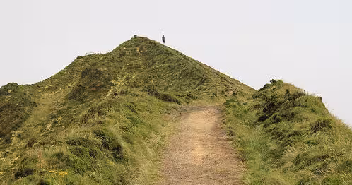 Hikers on a grassy volcanic ridge trail on the Seven Cities half-day walking tour in Sete Cidades, Azores