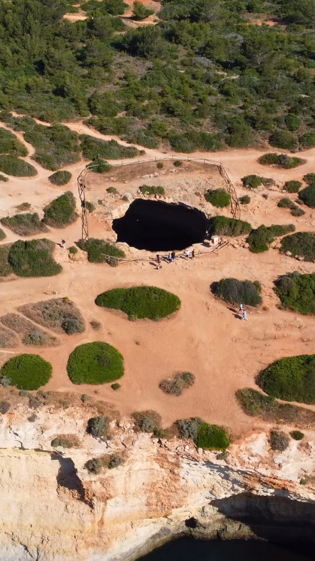 Aerial view of Seven Hanging Valleys trail overlooking Benagil cave sinkhole and rugged Algarve coastline in Portugal