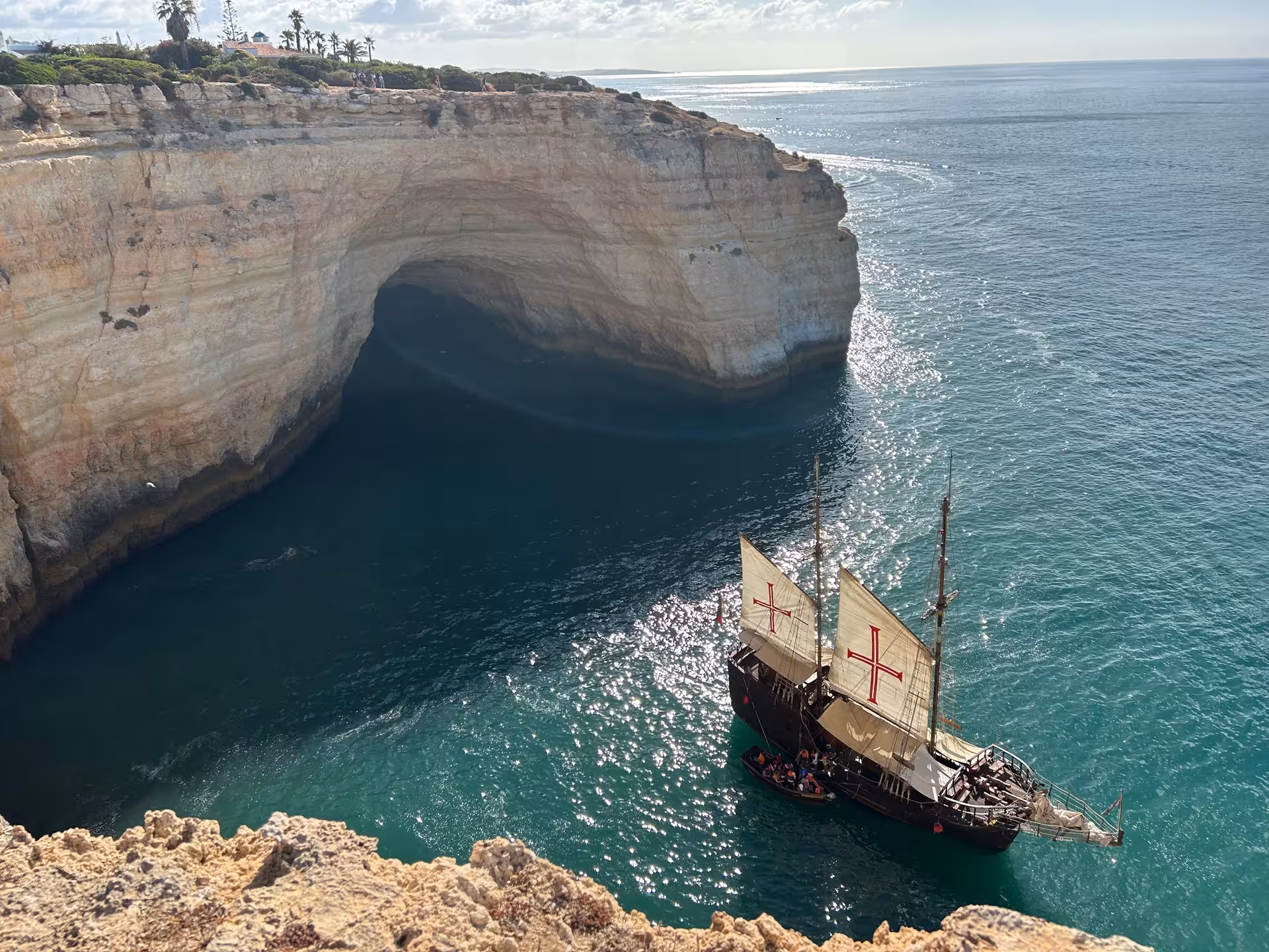Historic sailing ship exploring dramatic sea cave and turquoise coastal waters on the Seven Hanging Valleys trail Algarve