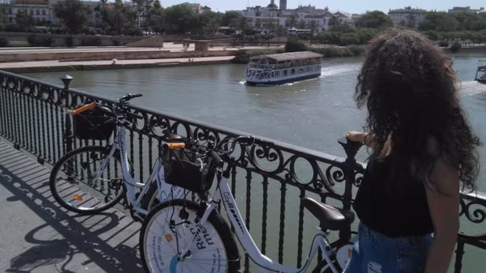 A woman admires the view of the Guadalquivir River from a bridge during a Seville bike tour.