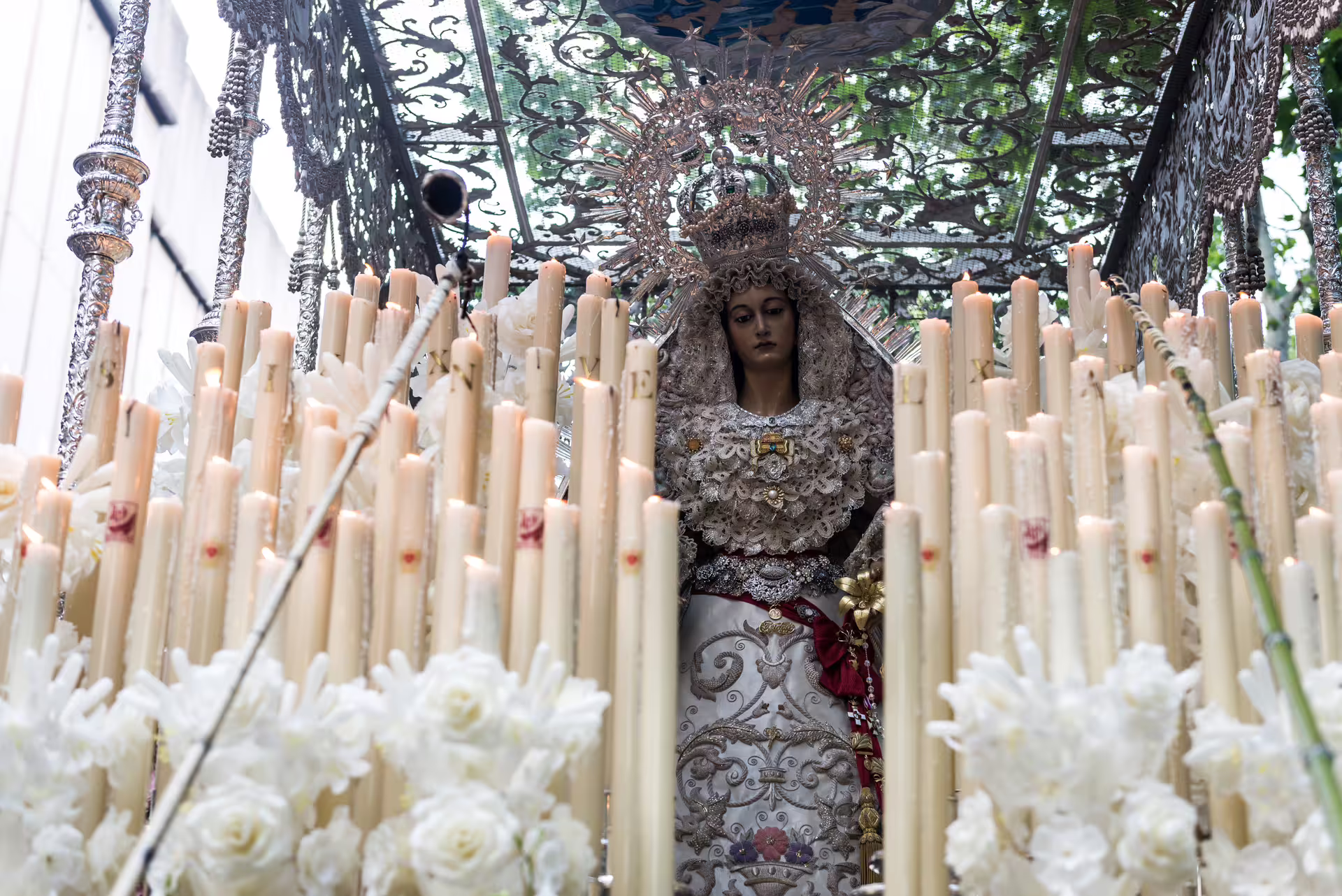 Intricate religious procession float adorned with candles and floral decorations during Seville's private Brotherhood tour.