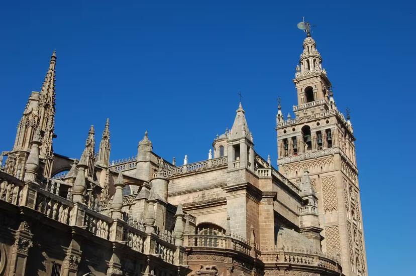The majestic Giralda tower and Seville Cathedral against a clear blue sky, a highlight of Seville's historic tour.