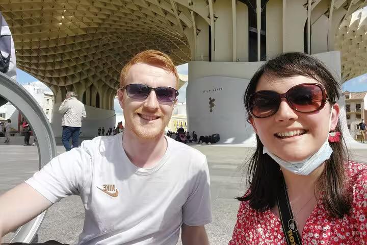 Two tourists smiling under the Metropol Parasol structure during a self-guided tour of Seville