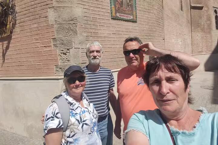 Group of four tourists taking a selfie in front of a historic brick building in Seville