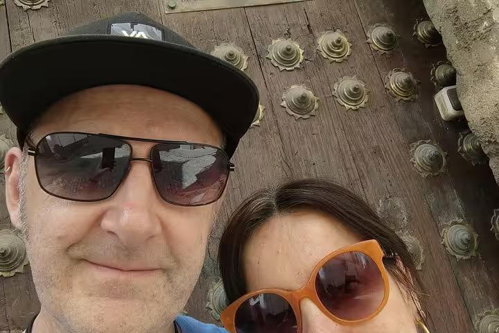 Couple taking selfie in front of ornate historic wooden door in Seville city tour