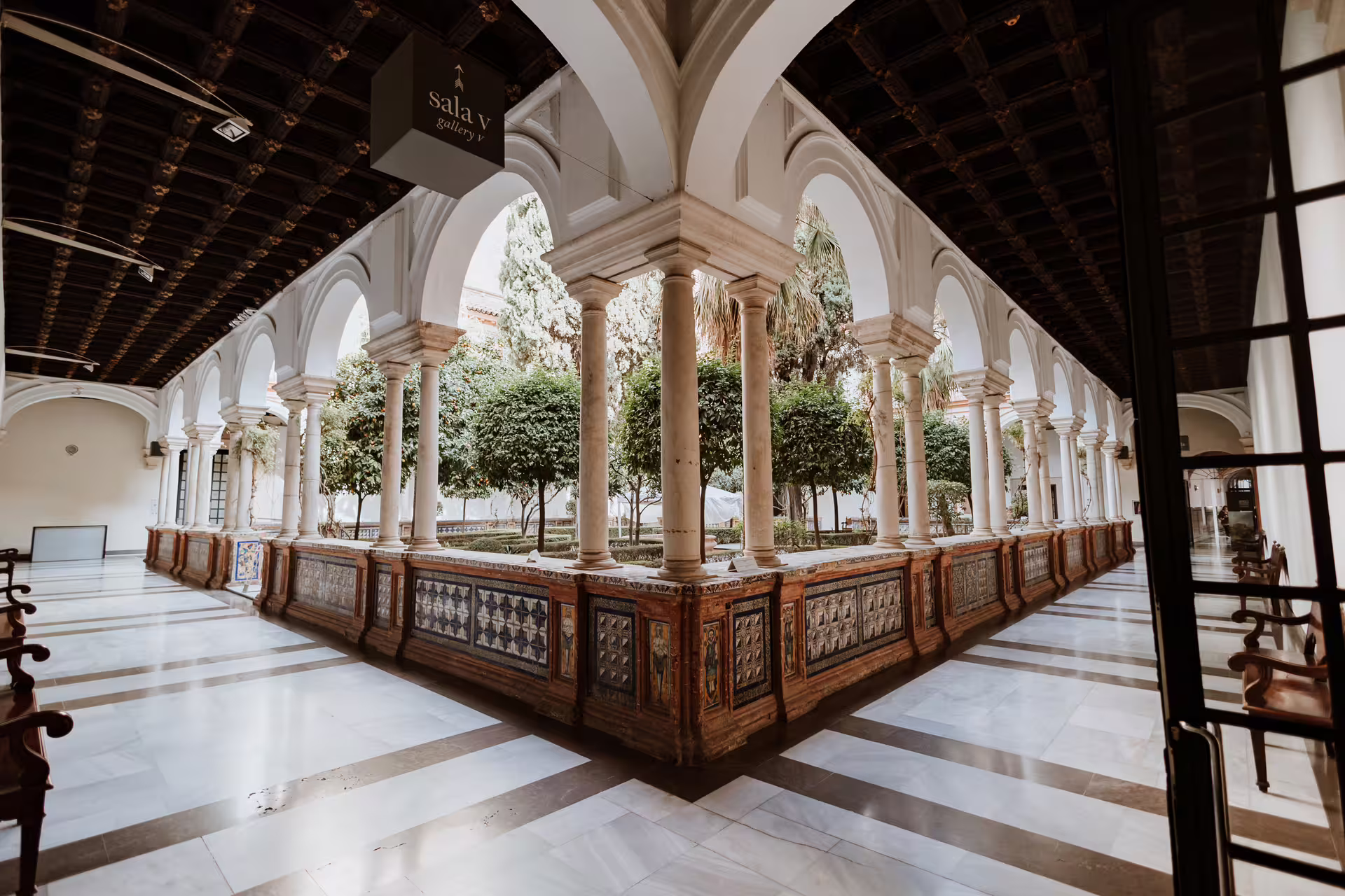 Elegant courtyard of Seville's Fine Arts Museum featuring arched walkways and lush greenery, perfect for cultural tours.