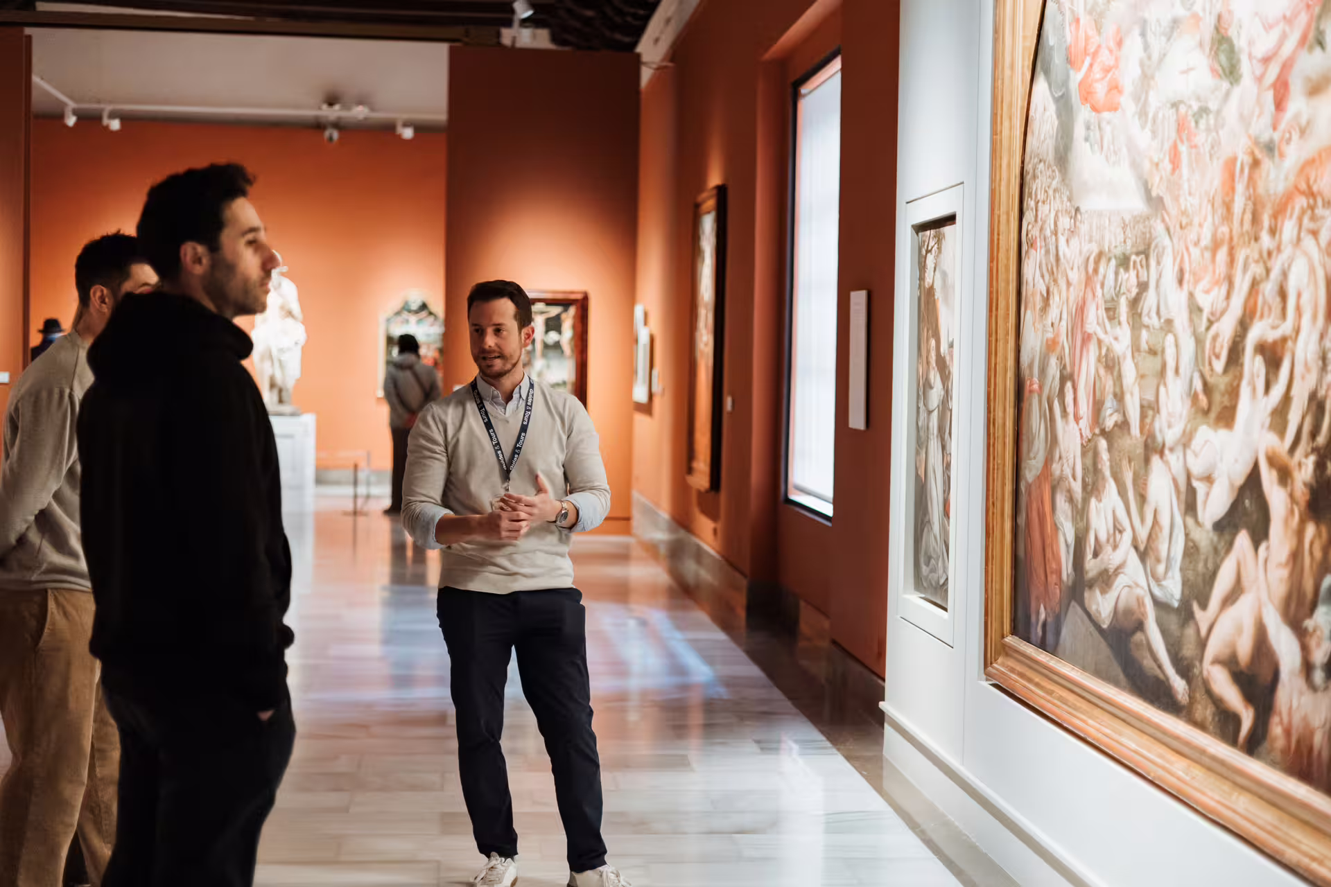 Visitors explore Seville's Fine Arts Museum with a guide, admiring classic paintings in a well-lit, elegant gallery space.