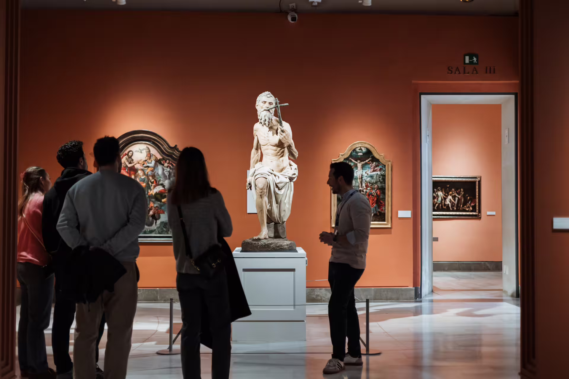Visitors admire classical sculptures and paintings in a vibrant gallery at Seville's Fine Arts Museum, enhancing their cultural tour.