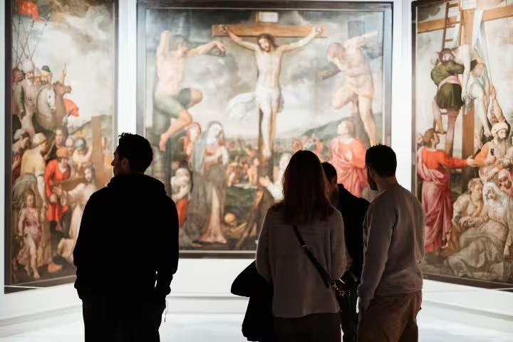 Visitors admire Renaissance paintings during a guided tour at Seville's Fine Arts Museum, highlighting cultural and historical art.