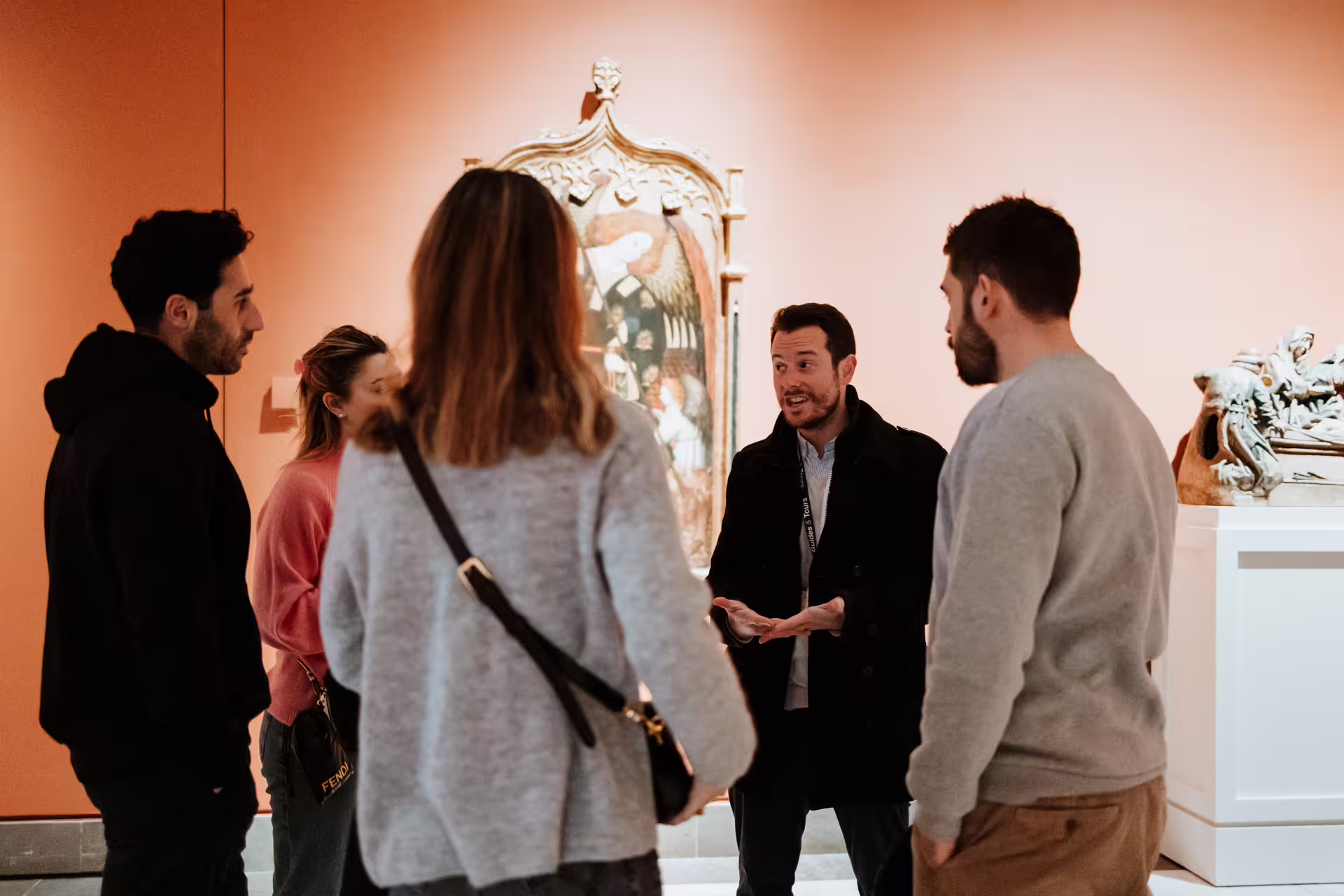 A group of tourists attentively listens to a guide in Seville's Fine Arts Museum, engaging with art and history.