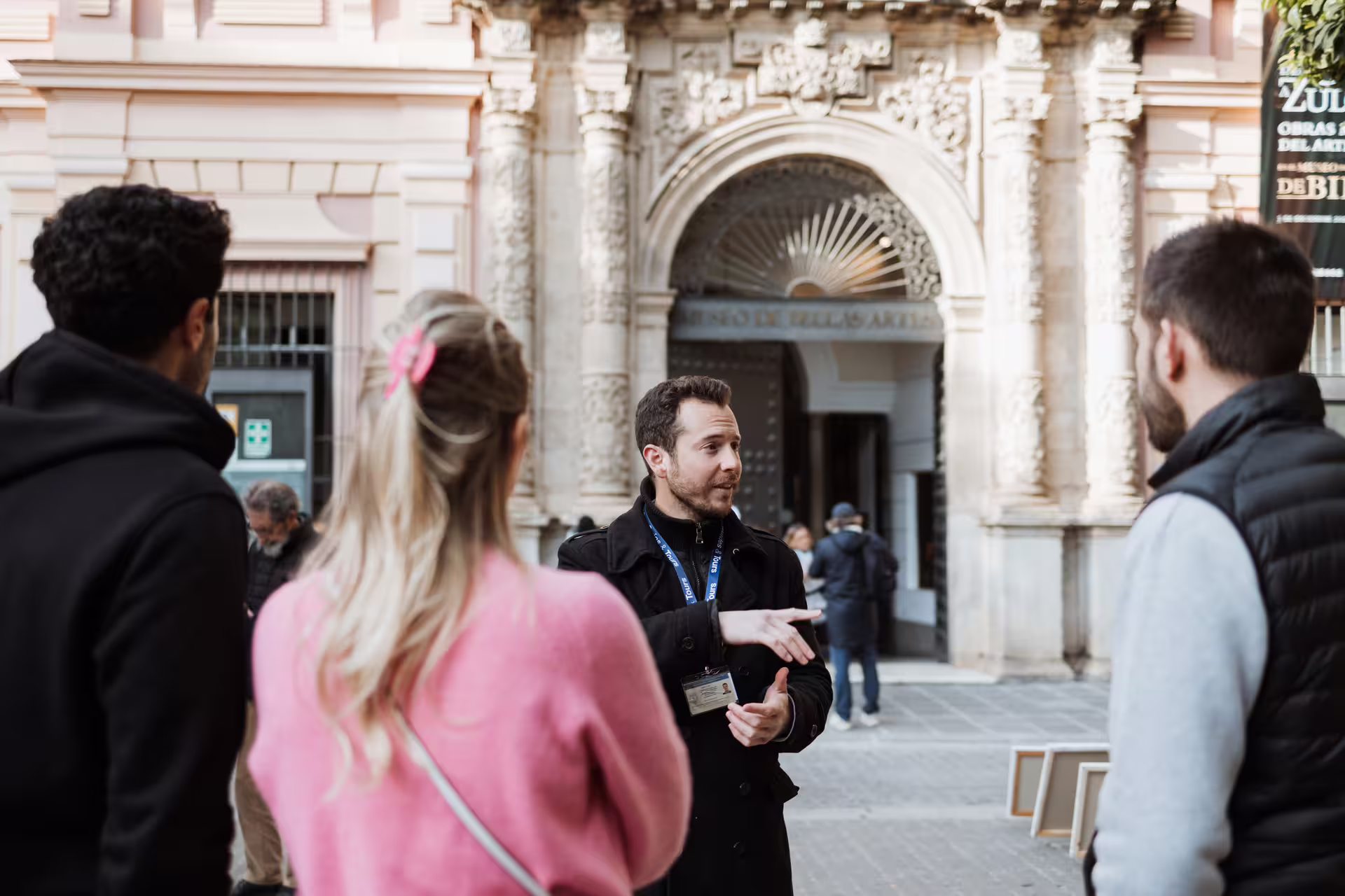 A tour guide leads visitors outside Seville's Fine Arts Museum, highlighting its stunning architecture and cultural significance.
