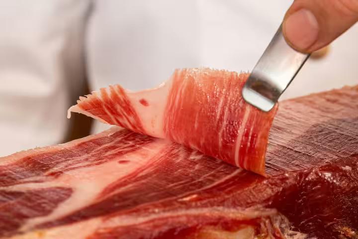 Slicing premium Iberian ham during a private food tour in Seville, showcasing authentic Spanish culinary experiences.