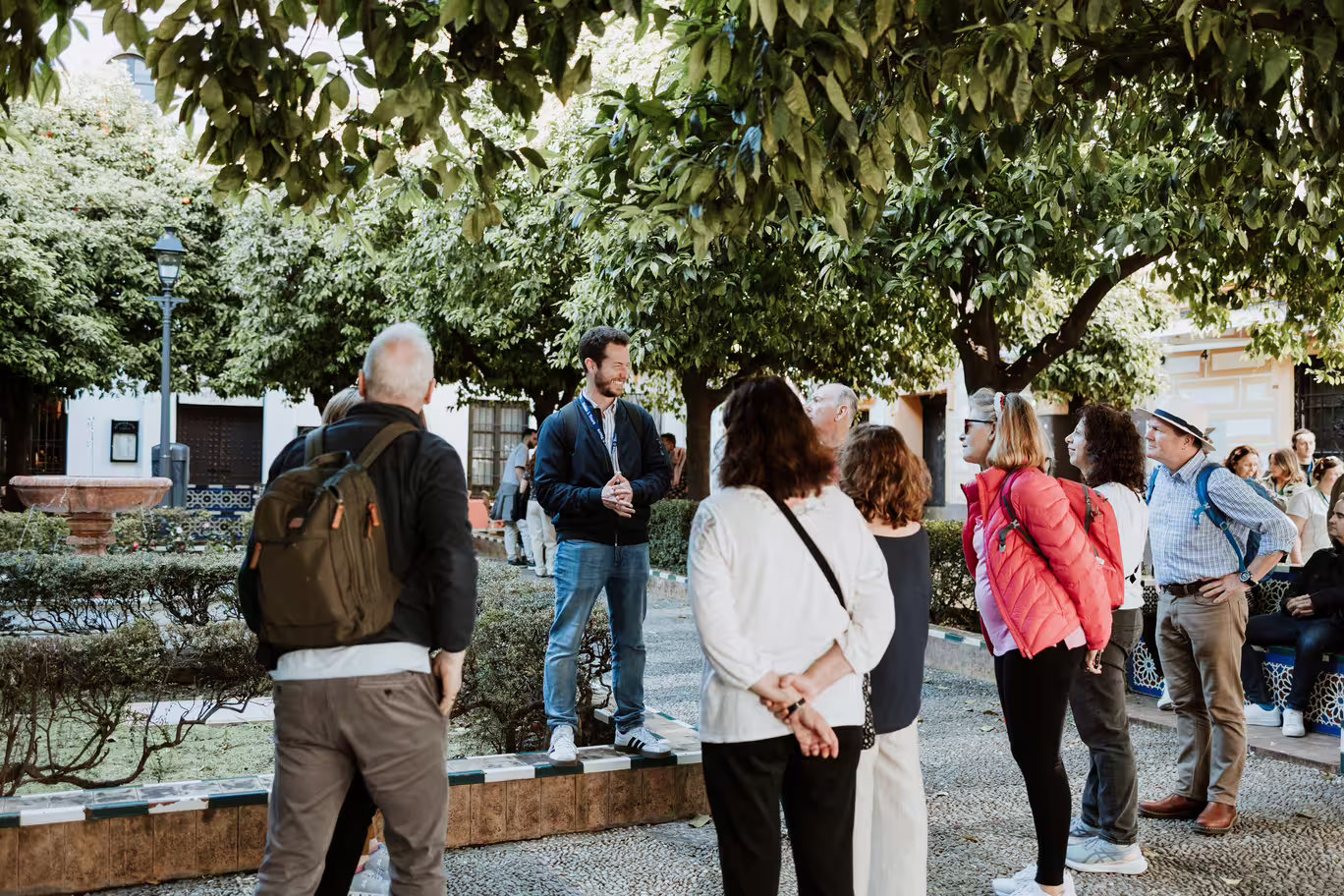 A tour guide leads a group in the lush gardens of Seville's Santa Cruz neighborhood, part of the Jewish Quarter tour.