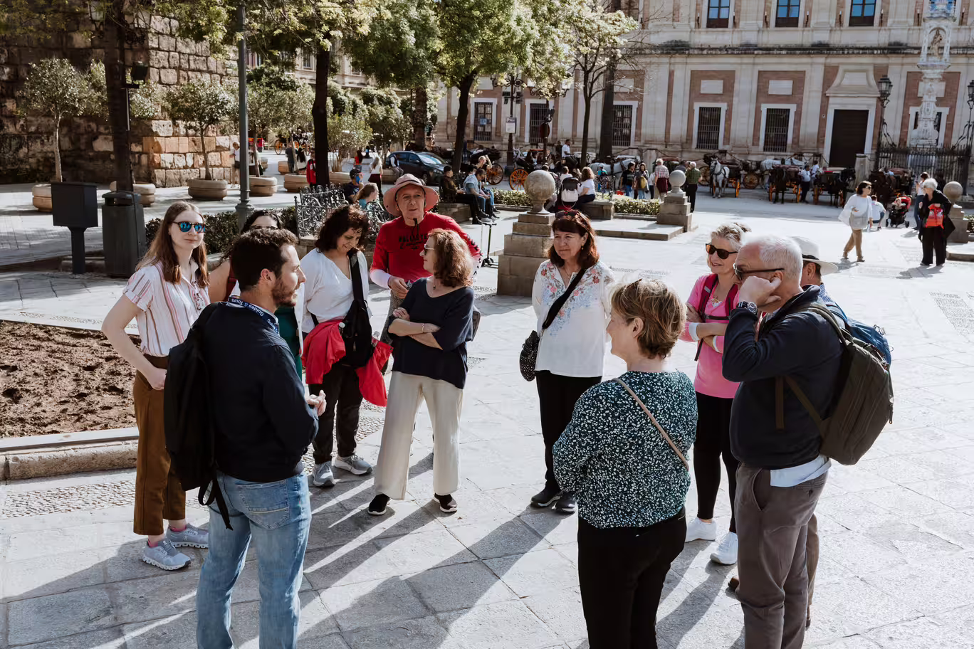 Group of tourists listening to a guide in Seville's historic Santa Cruz neighborhood, exploring Jewish heritage sites.