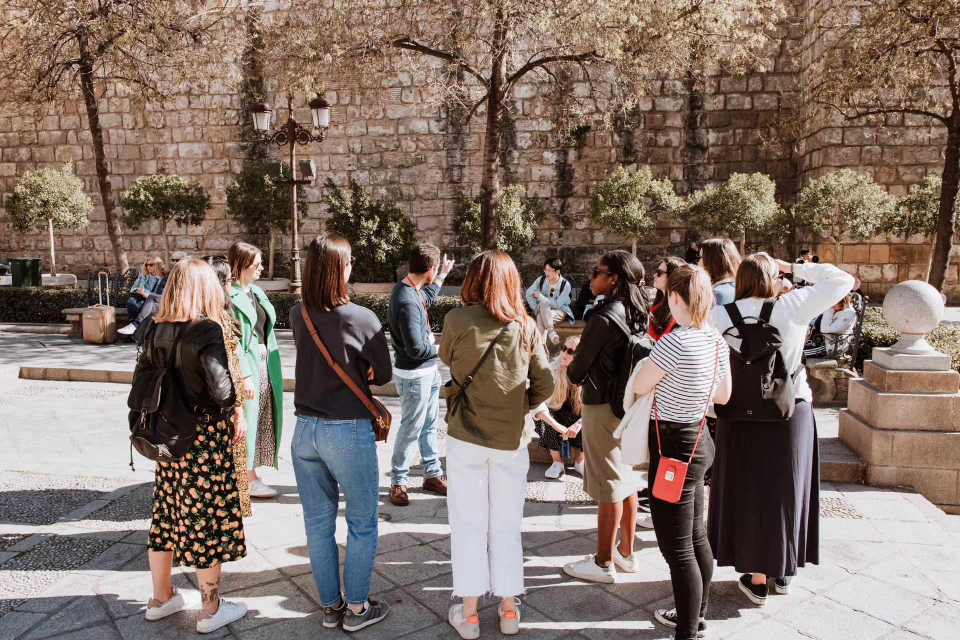 Guided tour group learning about Seville's Jewish Quarter history in picturesque Santa Cruz plaza.