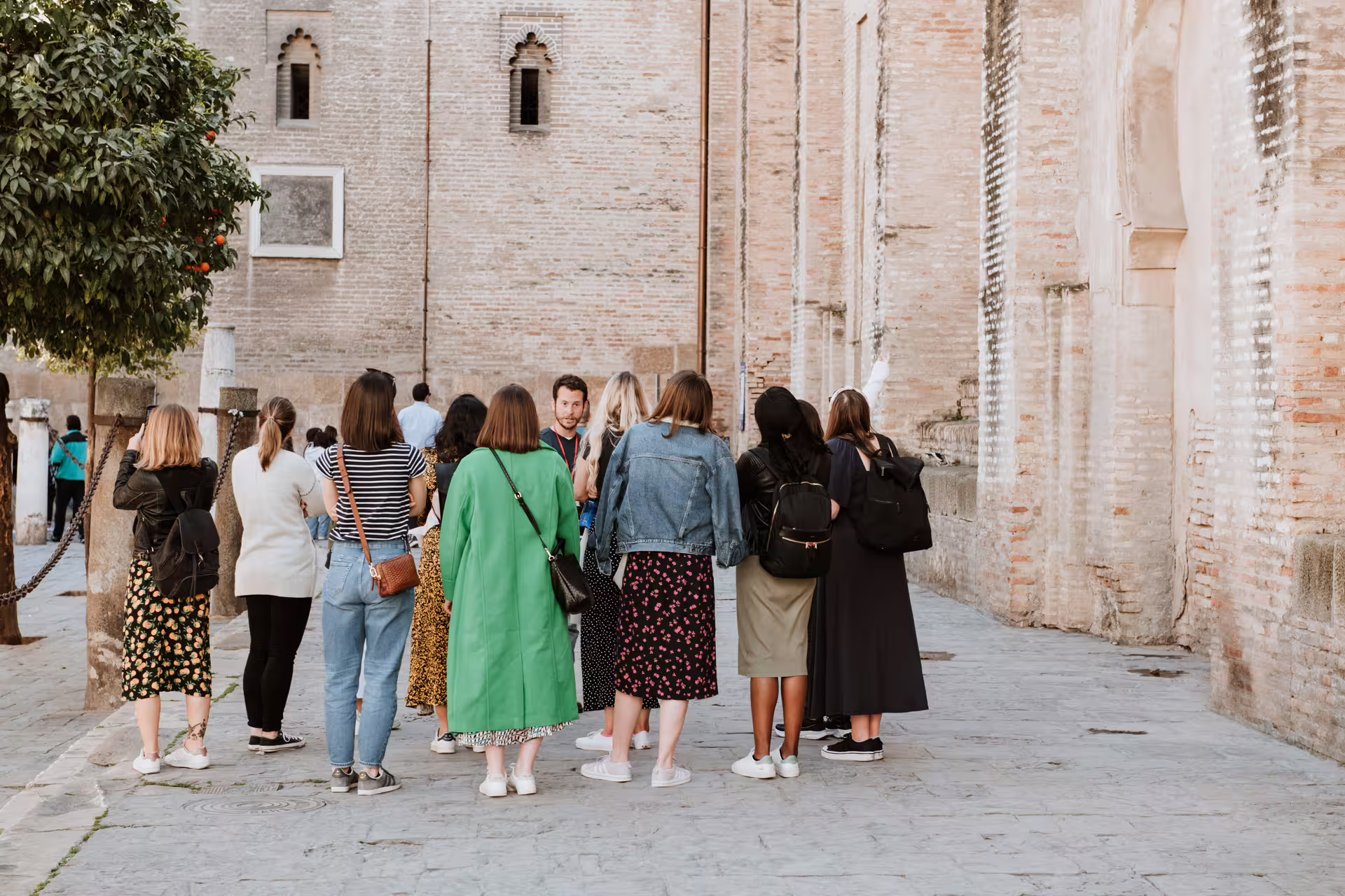 Tour group exploring the charming streets of Seville's Jewish Quarter, surrounded by historic brick buildings.