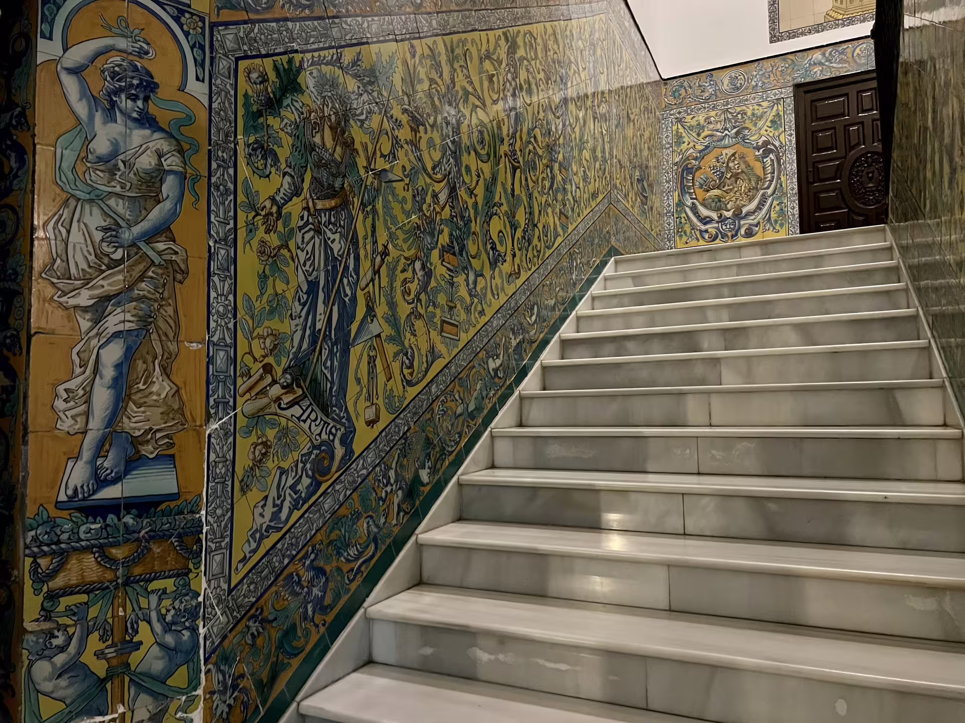Marble staircase adorned with intricate, mythical tile art in Seville, featured on the Mysterious and Paranormal Tour.