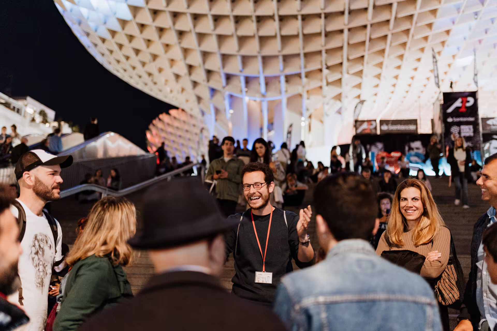A lively group gathers under Seville's illuminated Metropol Parasol for a thrilling mysterious and paranormal night tour experience.