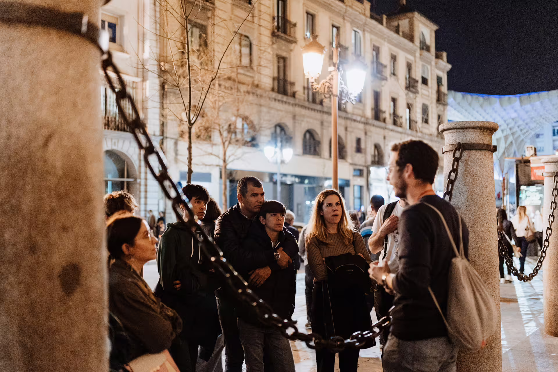 Tour guide leads group on Seville Mysterious and Paranormal Tour, exploring haunted sites by night in historic city center.