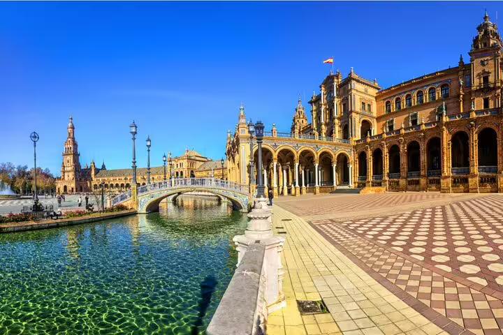 Plaza de España in Seville with ornate bridge over canal and grand Renaissance-Revival building under blue sky