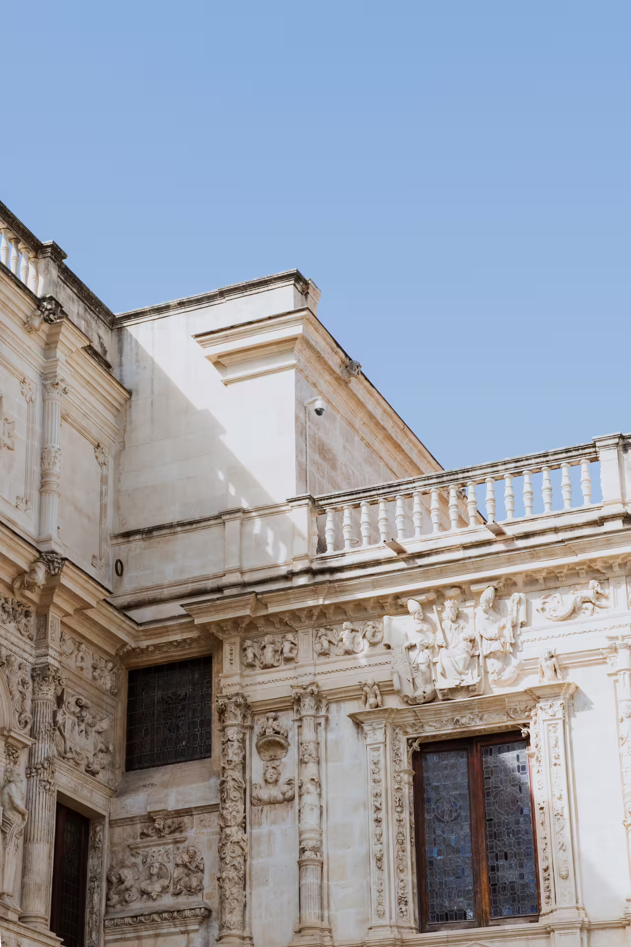 Intricate architectural details of a historic building in Seville's Santa Cruz neighborhood under a clear blue sky.