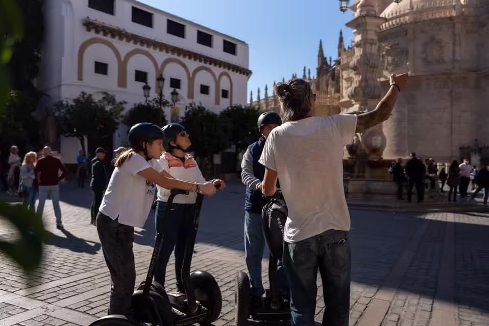 Tour guide points out landmarks to Segway riders in Seville's historic district on a sunny day.