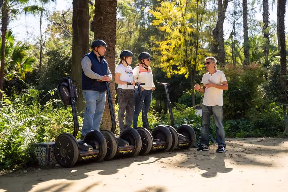 Tour guide instructs group on Segways in Seville's lush riverside park during 90-minute city tour.