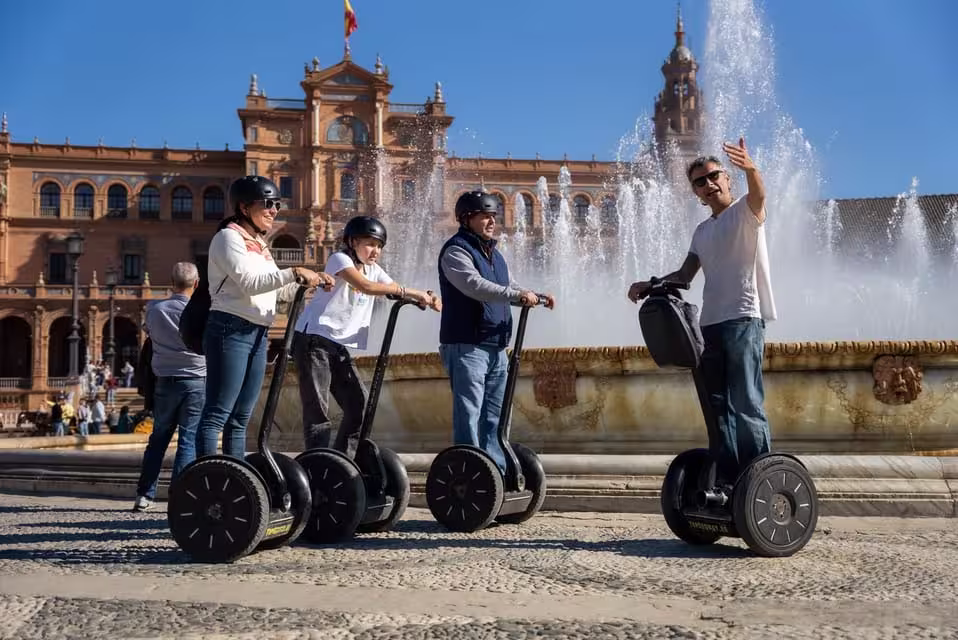 Tourists on Segways exploring the iconic Plaza de España fountain during a Seville city tour.