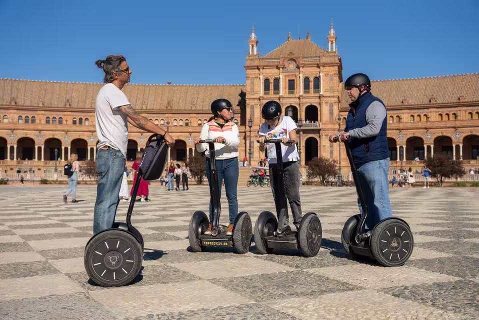 Riders on Segways explore Seville's iconic Plaza de España, led by guide on 90-minute city tour.