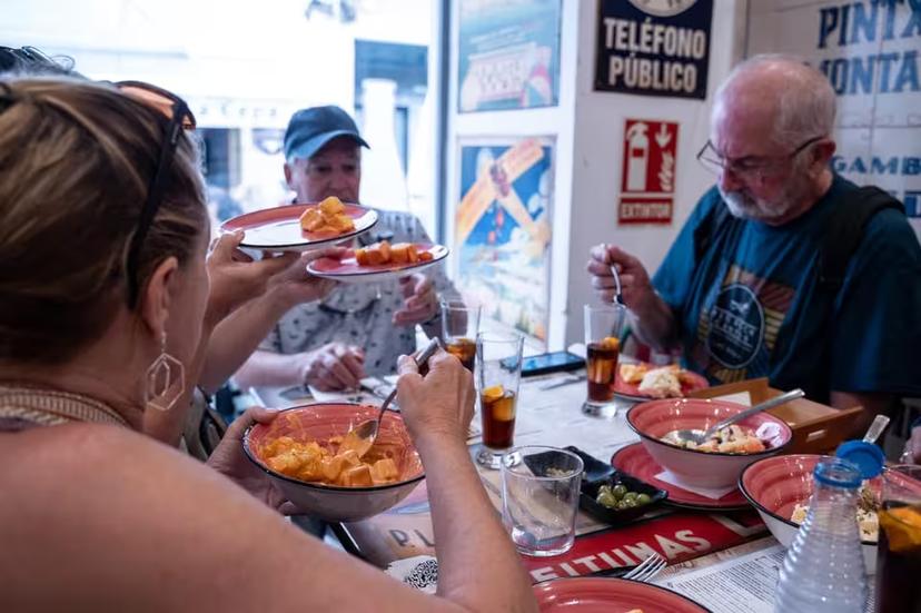 Group enjoying authentic tapas in a cozy Seville eatery during a historic walking tour experience.