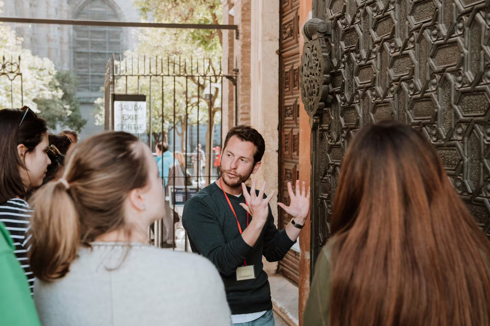 Tour guide explaining intricate details of Seville's historic architecture to a small group during a walking tour.
